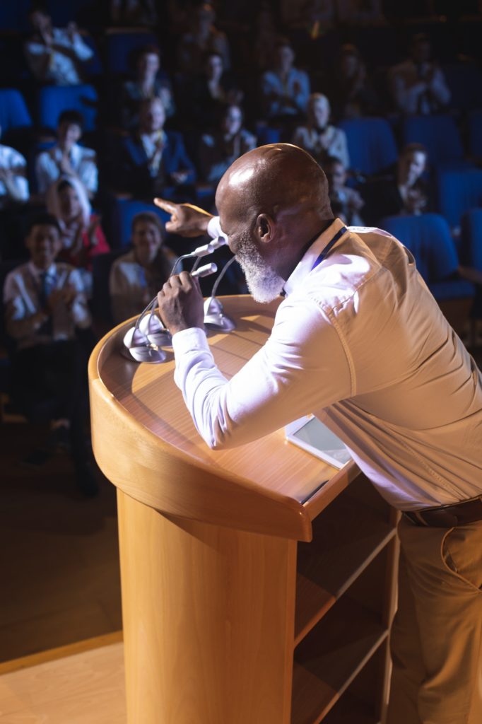 Businessman standing and holding speaker while asking question to the audience